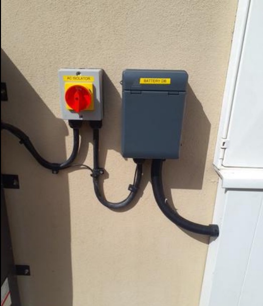 Close-up of the labelled AC isolator and battery distribution board with contained cable runs